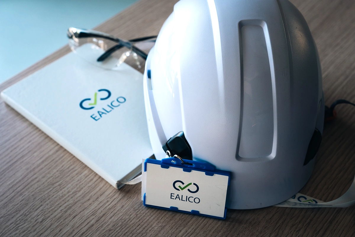 Casque de chantier et badge Ealico posés sur un bureau