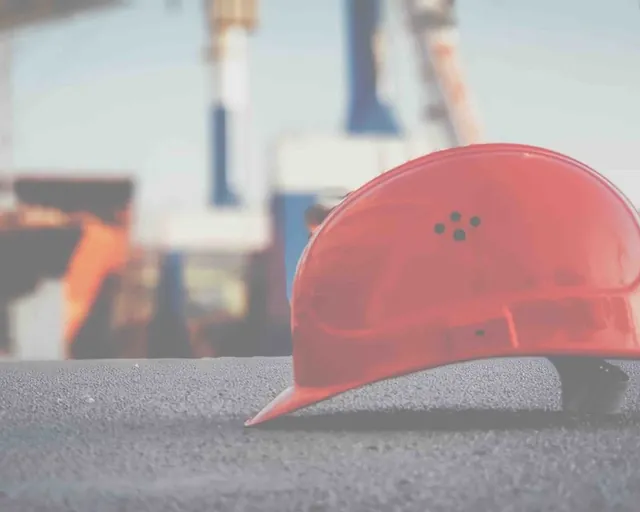 Casque de chantier rouge posé au sol sur un site portuaire