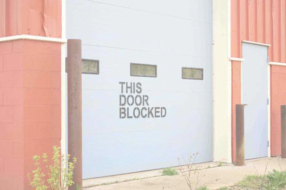 Porte industrielle sectionnelle et porte de service à l'entrée d'un bâtiment