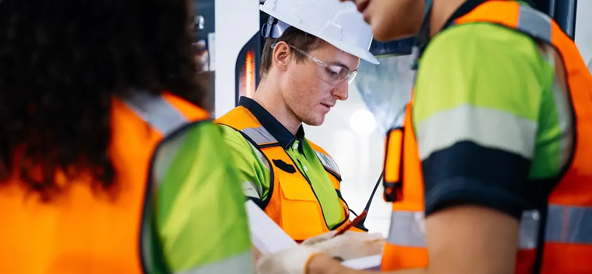 Technicien en équipement de protection renseignant un relevé de contrôle sur site